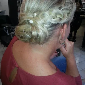 Coiffure spécial mariage. C'est un chignon plaqué avec des ornements à l'intérieur. On voit une tresse sur le côté.