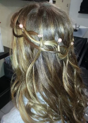 Coiffure de mariage. Ce sont des cheveux ondulés, avec des tresses qui forment une couronne. Il y a des ornement dans les tresses.