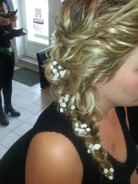 Coiffure de mariage. Tresse blonde de mariage avec ornement, elle est sur le côté.
